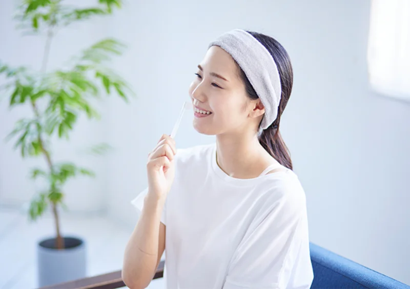 歯ブラシを手に笑顔で歯の定期検診を受ける女性